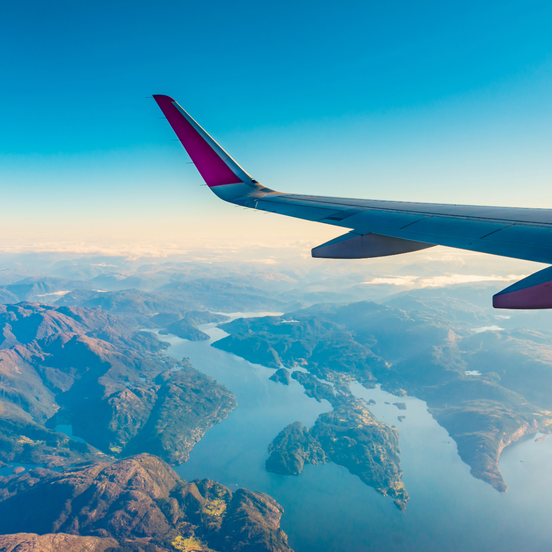 A plan flying over the sea with passengers talking about the difference between travel insurance and international health insurance.