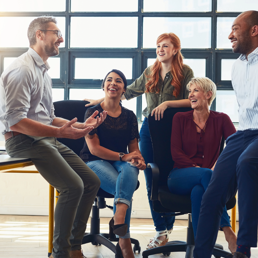 Happy team of diverse employees working together in an office, representing a positive workplace supported by employee benefits.