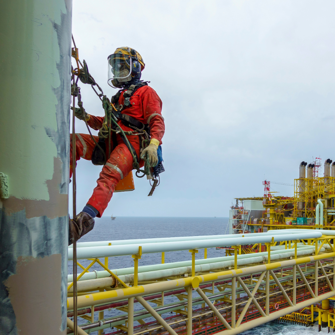 Oil Rig Workers Oil rig workers in safety gear on a platform at sea with sunset in the background, thinking about the importance of international insurance