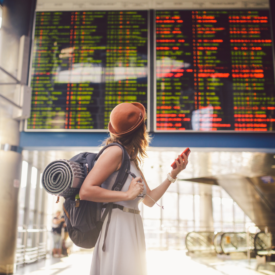 Traveller checking flight status screen at the airport, representing the importance of travel insurance.